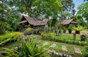 a garden with two huts with plants and flowers at แพนด้าแคมปิ้งเขาใหญ่ in Ban Khanong Phra Klang (1)