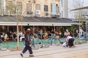 a person walking down a street with a crowd of people at Rena's House Smart Hotel in Tel Aviv +59 photos