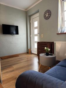 a living room with a couch and a table and a clock at Pension Adele - Ruhig, direkt am Elberadweg & Badesee mit Balkon in Dresden