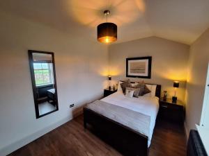 a bedroom with a large bed and a mirror at Luxurious Cottage Machrihanish in Drumlemble