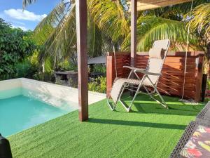 a chair on a lawn next to a swimming pool at Appartement charmant à Sainte-Rose de 40 m² avec piscine in Sainte-Rose
