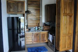 a kitchen with wooden cabinets and a black refrigerator at ONYX-- A Gem at DEE'S PEARL in Carriacou