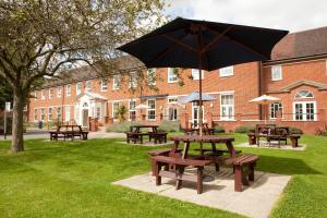 uma mesa de piquenique com um guarda-chuva em frente a um edifício em Mitchell Hall em Cranfield