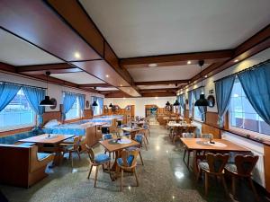 a restaurant with wooden tables and chairs and windows at M1 Laczházy Hotel Coffee & More in Mocsa