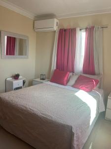 a bedroom with a large bed and pink curtains at Vista al Caribe in Los Mameyes