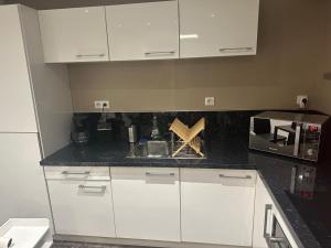 a kitchen with white cabinets and a black counter top at Appartement rez de chaussée 4 personnes 2 chambres avec parking in Coudekerque-Branche +11 photos
