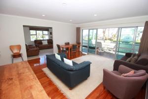 a living room with a couch and chairs and a table at Tindalls Bay Beach House in Whangaparaoa
