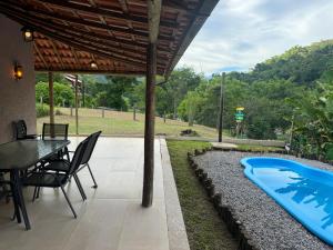 a patio with a table and a swimming pool at Serra Mar à beira rio , rafting, suites, lofts, e Casas in Sana