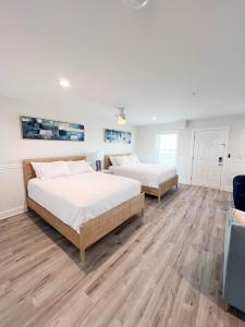 two beds in a large room with wooden floors at 3002 Queen Suite, 3rd Floor Surfside in Surf City