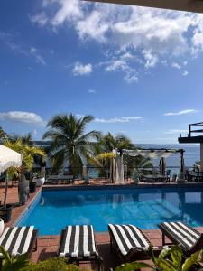 a swimming pool with lounge chairs and the ocean at Villa Condesa Del Mar in Contadora