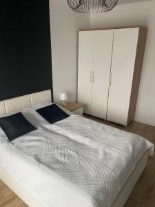 a bedroom with a white bed and a white cabinet at Black & White Dziwnów in Dziwnów