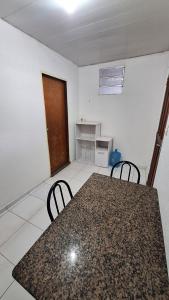 a room with a table and two chairs and a door at Hospedagem simples em Manaus in Manaus