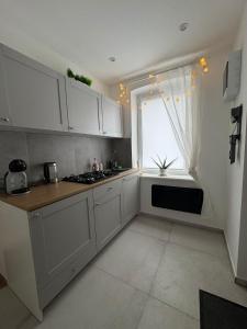 Una cocina con gabinetes blancos y una ventana. en Mieszkanie na wynajem BOHO, en Lipno