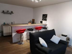 a living room with a black couch and red stools at Ananas in Riorges