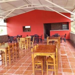 a room with wooden tables and chairs and a red wall at Casa campestre con piscina natural in Chipaque