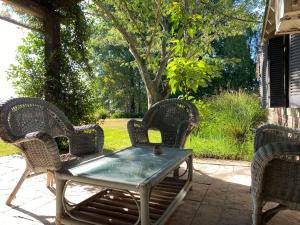 a patio table with three wicker chairs and a table with at CHACRA con VISTA AL CAMPO DE POLO in Pilar