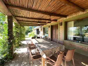 a patio with a table and chairs under a wooden pergola at CHACRA con VISTA AL CAMPO DE POLO in Pilar