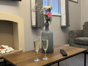 two glasses of champagne and a vase on a coffee table at Omega Apartment - 3 Bedrooms - Sleeps 5 in Whitehaven