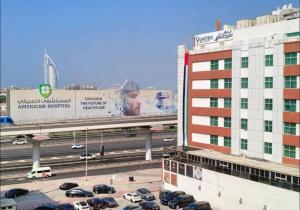 a parking lot with cars on a highway next to a building at Partition Room with window Near Mashreq Metro in Dubai +4 photos