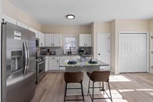 a kitchen with a refrigerator and a counter with chairs at 3BD Retreat - Hot Tub & BBQ - Near NCSU & Downtown in Raleigh