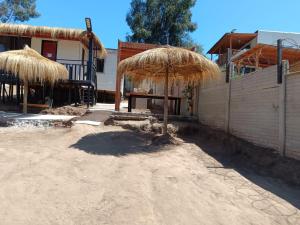 a patio with a table and a straw umbrella at Cabañas Martina in Cartagena