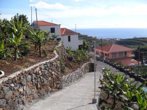 a stone wall next to a road with houses at Fazenda do Sousinha in Funchal