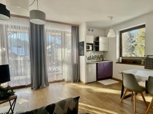 シュツァブニツァにあるApartamenty Kornajeのリビングルーム(テーブル付)、窓付きのキッチンが備わります。