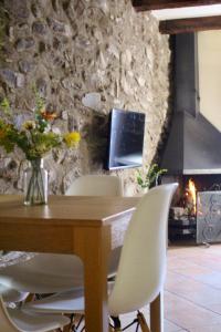 a table with white chairs and a television and a fireplace at Apartament Cal Barracaire in Vilallonga de Ter