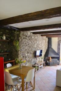a dining room with a table and a stone wall at Apartament Cal Barracaire in Vilallonga de Ter