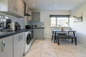 a kitchen with a washing machine and a table at 4br-sleeps8-privategarden-freeparking in Nottingham +8 photos