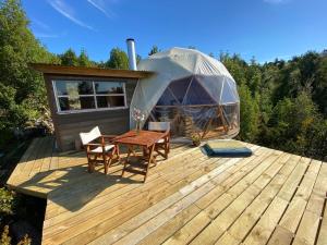 a yurt with a table and chairs on a wooden deck at Domobosque in Ancud
