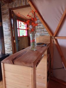 a vase of flowers on a wooden table in a room at Domobosque in Ancud