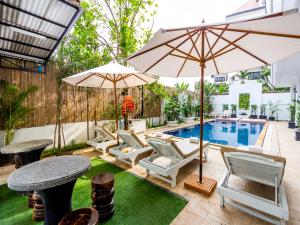 a patio with a pool and chairs and umbrellas at Rithy Rine Angkor Residence in Siem Reap