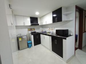 a kitchen with black and white cabinets and a refrigerator at Apartamento Estadía Ideal in Duitama