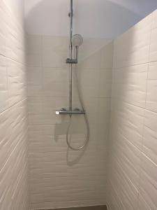 eine Dusche mit Schlauch in einem weiß gefliesten Badezimmer in der Unterkunft Charmante maison du XVIII en pierre rénovée in Colleville-Montgomery