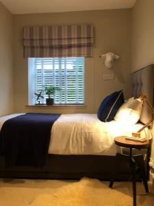 ein Schlafzimmer mit einem Bett mit Fenster und einem Tisch in der Unterkunft Cottage c1790, Superb central Witney, free parking in Witney