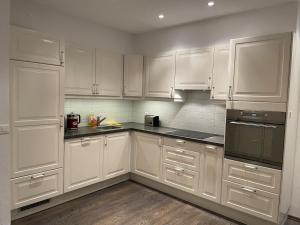 a white kitchen with white cabinets and black appliances at Apartment with Pool, Sauna & Gym in Laax