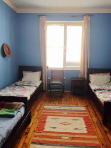 a room with two beds and a window and a rug at Interhost Guest rooms and apartments in Sofia