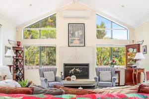 a living room with a fireplace and two chairs at Annabells B&B in Whitianga