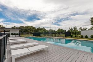 a swimming pool with benches next to a wooden deck at Cosy 1-Bed with Pool, Gym and Secure Parking in Phillip