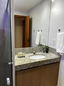 ein Badezimmer mit Waschbecken und Spiegel in der Unterkunft Village Itacimirim Boulevard - Pé na areia in Itacimirim