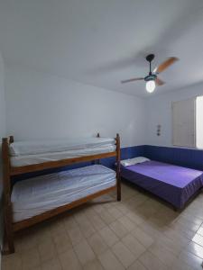 two bunk beds in a room with a ceiling fan at Casa Térrea Pet Friendly 8 Pessoas Ubatuba in Ubatuba