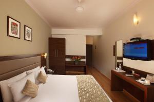 パナジにあるザ ハワイコンフォーツのベッド1台、薄型テレビが備わるホテルルームです。
