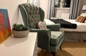 ein Schlafzimmer mit einem grünen Stuhl und einem Bett in der Unterkunft Beautiful Rooms near Hampton Court in Molesey