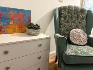 ein Stuhl neben einer Kommode neben einem Gemälde in der Unterkunft Beautiful Rooms near Hampton Court in Molesey + 23 Fotos