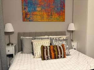 ein Schlafzimmer mit einem Bett mit Kissen und einem Gemälde in der Unterkunft Beautiful Rooms near Hampton Court in Molesey