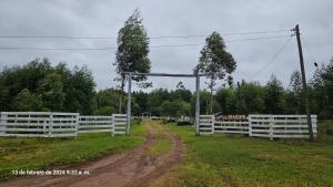 a white fence in a field with a dirt road at Chacra Don Joaquin 1 in La Cruz