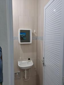 baño con lavabo y TV en la pared en Tô em casa Tamandaré, en Tamandaré