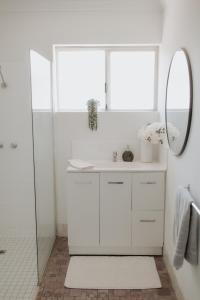 une salle de bain blanche avec un lavabo et un miroir dans l'établissement Serene Stay Near Perth & Freo, à Bicton