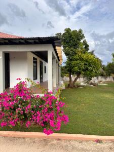 a house with pink flowers in front of it at Beachscape At Black River Zermatt in Black River